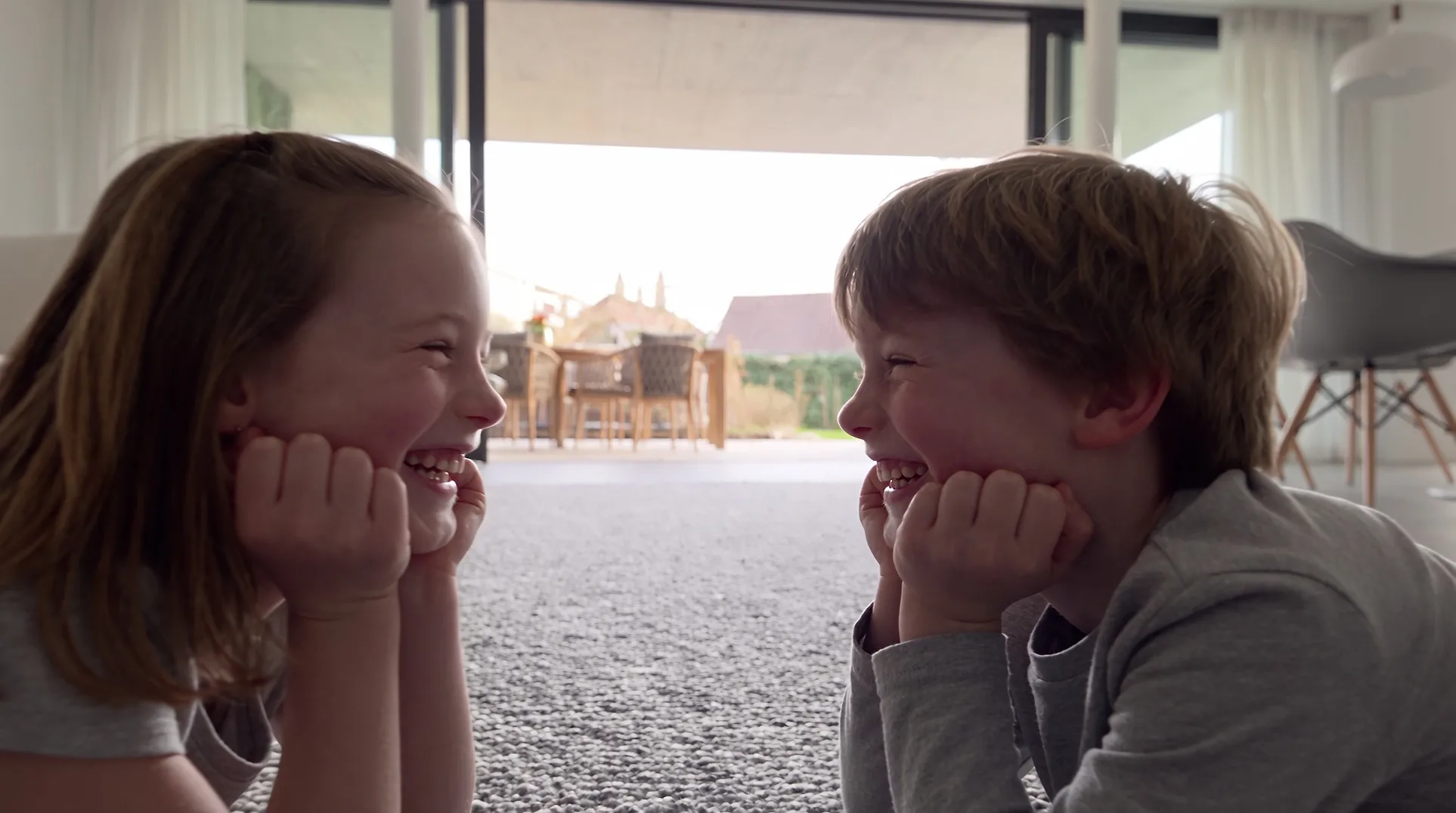 Brother and sister laughing on the living room rug